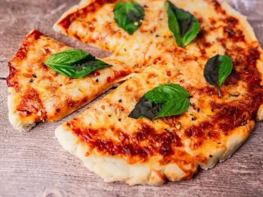 Pyszna pizza z air fryera, z ciągnącym się serem i świeżą bazylią, wygląda apetycznie na drewnianym blacie.