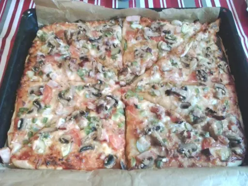Pyszna pizza na grubym cieście z pieczarkami, pomidorami i papryką, prosto z blachy.