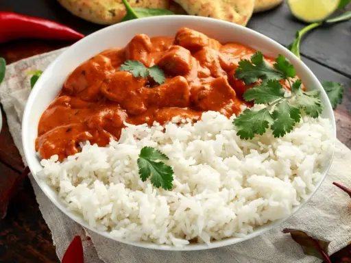 Aksamitny kurczak tikka masala w kremowym sosie, podany z puszystym ryżem i świeżą kolendrą.