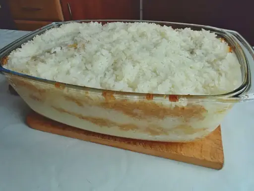 Pyszny, domowy ryż z jabłkami w szklanej formie, gotowy do pieczenia.
