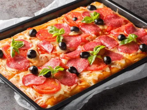 Chrupiąca pizza z ciasta francuskiego z salami, pomidorami, oliwkami i bazylią, prosto z blachy.