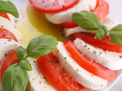 Sałatka z mozzarellą, pomidorami i bazylią, skropiona oliwą i pieprzem. Klasyczne połączenie smaków.
