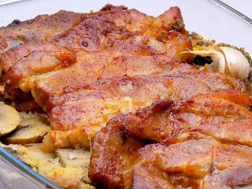 Soczysta karkówka z pieczarkami i ziemniakami, zapieczona w szklanym naczyniu. Aromatyczny czosnek dodaje głębi smaku.