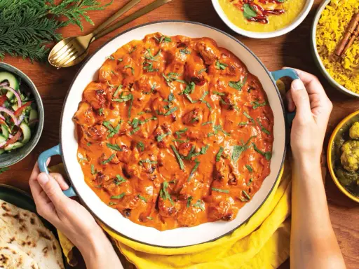 Pyszny butter chicken przepis w kremowym sosie, podany z ryżem, sałatką i chlebkiem naan.