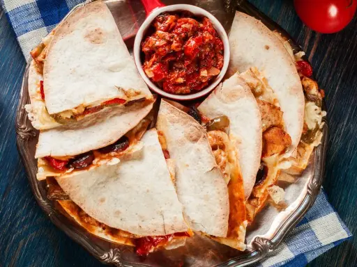 Pyszna quesadilla z kurczakiem, podana z salsą pomidorową na srebrnej tacy. Idealna na szybki posiłek.