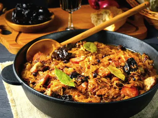 Ania gotuje pyszny bigos w żeliwnym naczyniu, pełen kapusty, mięsa i śliwek.