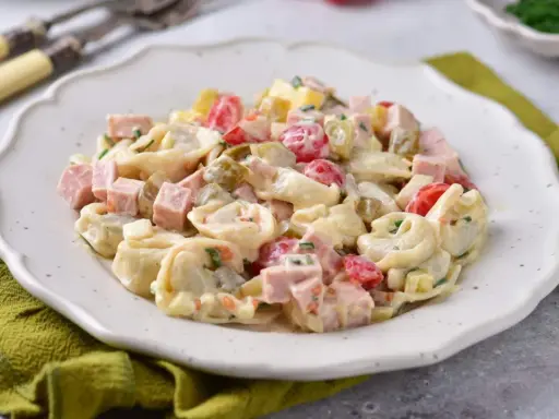 Pyszna sałatka z tortellini, szynki, pomidorków i ogórków konserwowych w kremowym sosie. Idealna na każdą okazję.