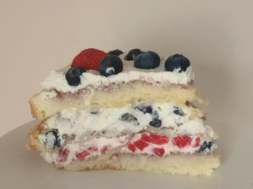 Pyszne ciasto na biszkopcie z bitą śmietaną, truskawkami i borówkami. Idealne na letnie popołudnie.