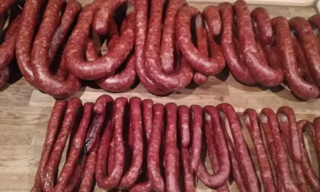 Dwie linie świeżo uwędzonej, prawdziwej wiejskiej kiełbasy, gotowe do podania. Przepis na domową kiełbasę jest w zasięgu ręki!
