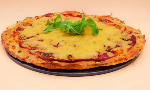 Chrupiąca pizza z serka wiejskiego, pokryta ciągnącym się serem i świeżą rukolą. Idealna na szybki obiad.
