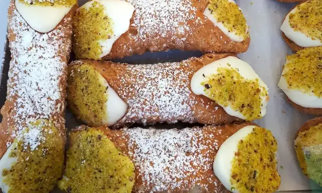 Pyszne rurki z kremem, posypane cukrem pudrem i pistacjami, kuszą swoim wyglądem.