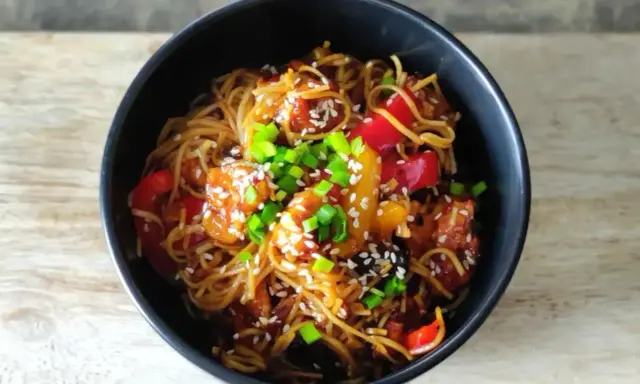 Pyszny makaron chow mein z kurczakiem, papryką i szczypiorkiem, posypany sezamem.