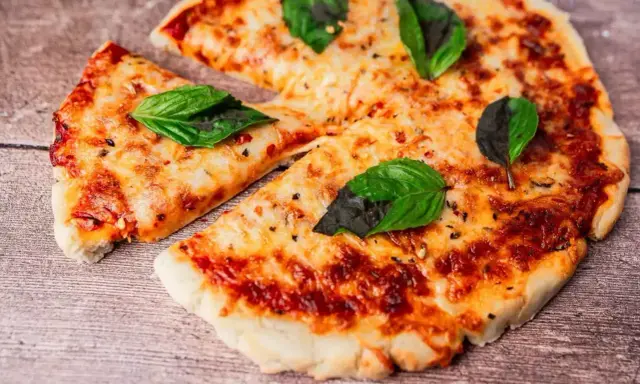 Pyszna pizza z air fryera, z ciągnącym się serem i świeżą bazylią, wygląda apetycznie na drewnianym blacie.