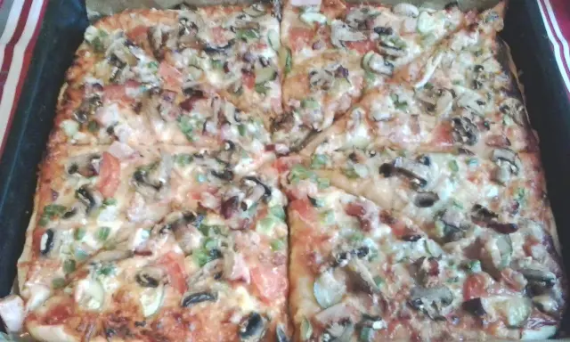 Pyszna pizza na grubym cieście z pieczarkami, pomidorami i papryką, prosto z blachy.