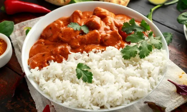 Aksamitny kurczak tikka masala w kremowym sosie, podany z puszystym ryżem i świeżą kolendrą.