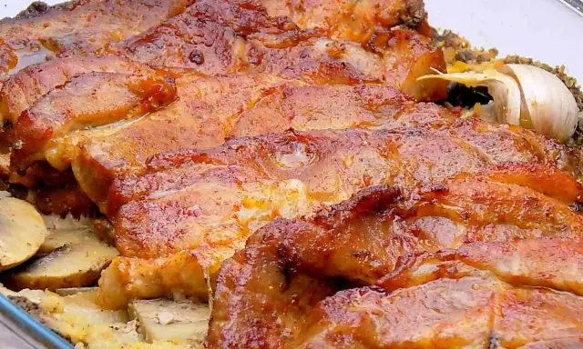 Soczysta karkówka z pieczarkami i ziemniakami, zapieczona w szklanym naczyniu. Aromatyczny czosnek dodaje głębi smaku.