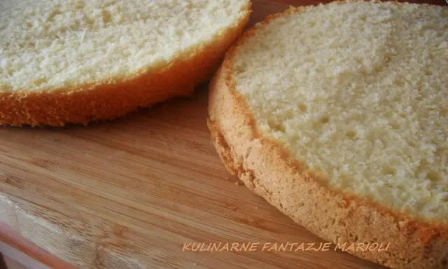 Dwa puszyste krążki biszkoptu z 4 jaj na drewnianej desce, gotowe do dekoracji.