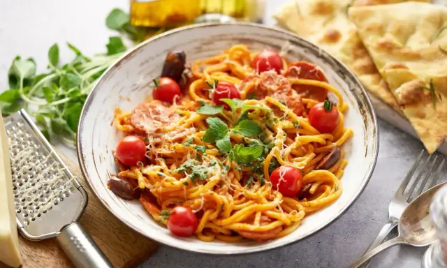 Pyszny makaron z chorizo, pomidorkami koktajlowymi i świeżą bazylią, posypany parmezanem. Idealny na szybki obiad.