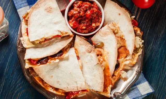 Pyszna quesadilla z kurczakiem, podana z salsą pomidorową na srebrnej tacy. Idealna na szybki posiłek.