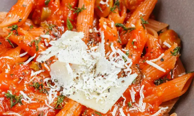 Penne w sosie pomidorowym z oliwkami i parmezanem. Idealny szybki obiad z makaronem, doprawiony ziołami.