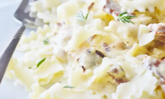 Pyszny makaron farfalle w kremowym sosie śmietanowym z kawałkami boczku i świeżym rozmarynem.