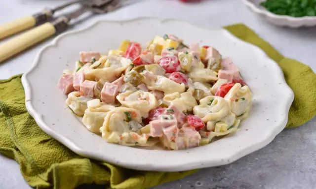 Pyszna sałatka z tortellini, szynki, pomidorków i ogórków konserwowych w kremowym sosie. Idealna na każdą okazję.