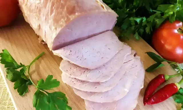 Schab gotowany 2 razy po 10 minut, pokrojony w plastry, z pomidorami i papryczkami chili na desce.