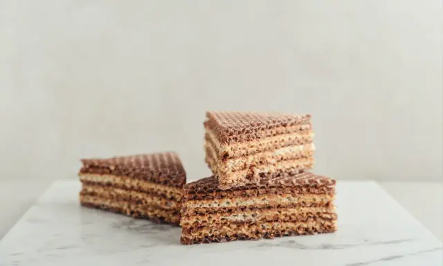 Słodkie wafle z kajmakiem, ułożone na marmurowym blacie, kuszą chrupiącą teksturą i kremowym nadzieniem.