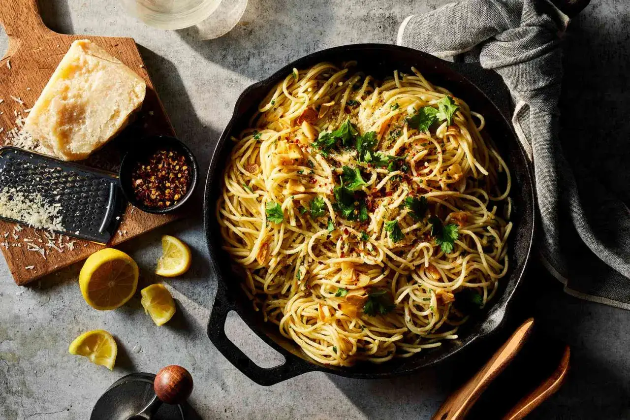 Pyszne dania z makaronem: spaghetti aglio e olio z czosnkiem, chili i natką pietruszki, podane z parmezanem i cytryną.