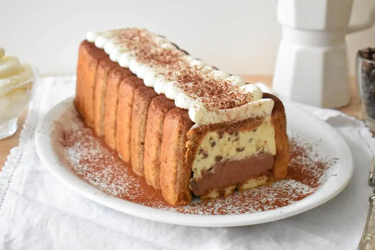 Pyszne ciasto z mascarpone, przełożone kremem i czekoladą, otulone biszkoptami i posypane kakao. Idealne na deser.