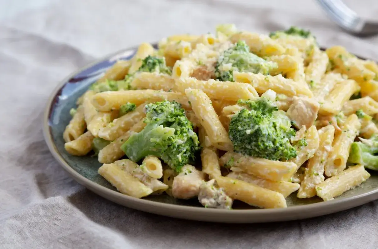 Penne z kurczakiem i brokułami w kremowym sosie, posypane parmezanem. Pyszne danie obiadowe.