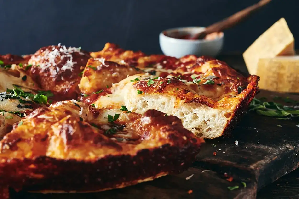 Pyszna pizza domowa przepis na blachę, z chrupiącym ciastem i ciągnącym serem. Idealna na rodzinny obiad.