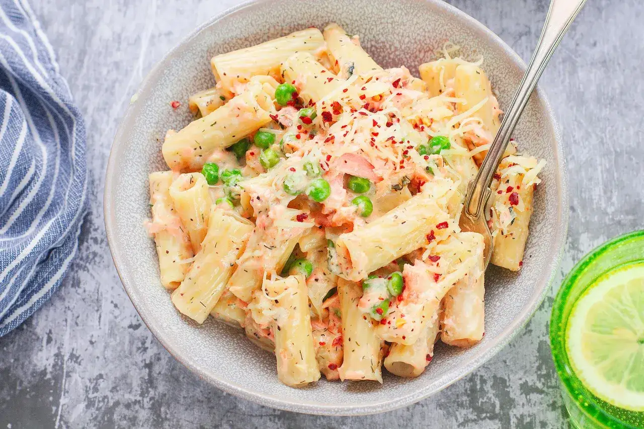 Pyszne makaron z łososiem, groszkiem i parmezanem, posypany płatkami chili. Idealny na szybki obiad.