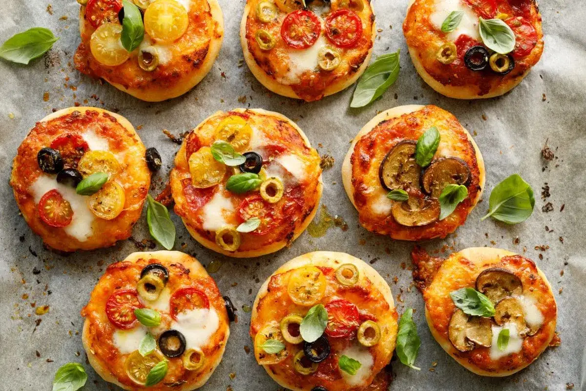 Pizzerinki z ciasta francuskiego z pomidorkami, oliwkami i bazylią. Niektóre z pieczarkami.