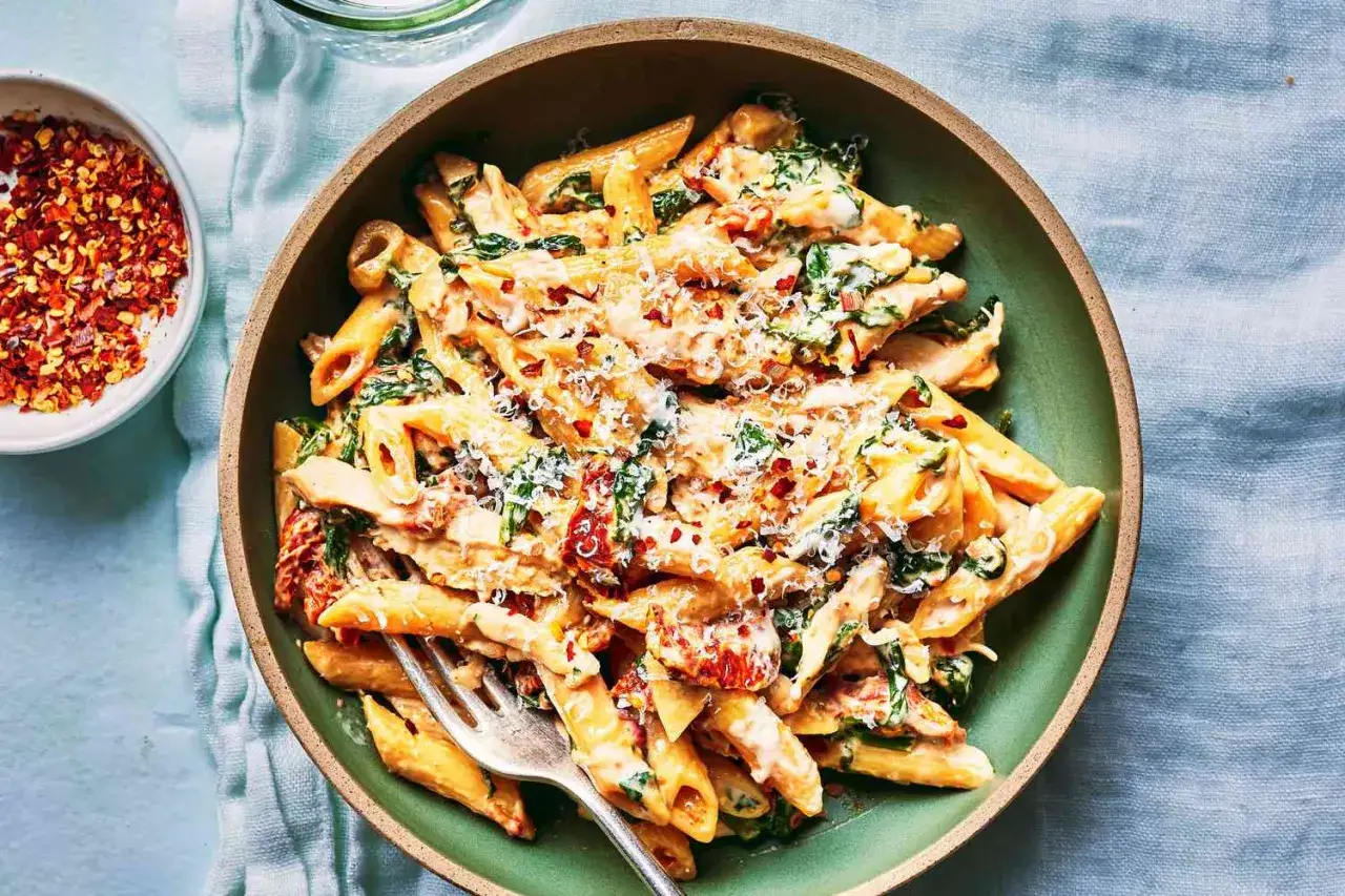 Penne z kremowym sosem, szpinakiem i suszonymi pomidorami, posypane parmezanem i płatkami chili. Pyszne danie, które zachwyci każdego.