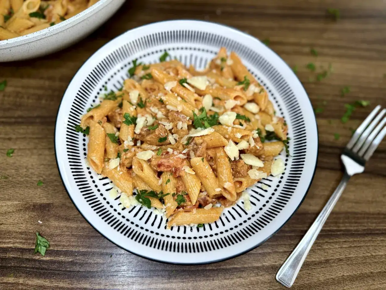 Penne z kremowym sosem pomidorowym i kawałkami pikantnego chorizo, posypane parmezanem i natką pietruszki.