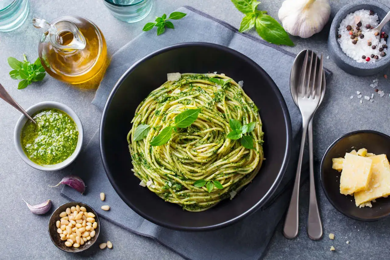 Pyszny obiad bez mięsa: spaghetti z pesto, świeżą bazylią, orzeszkami pinii i parmezanem. Idealne dla wegetarian.