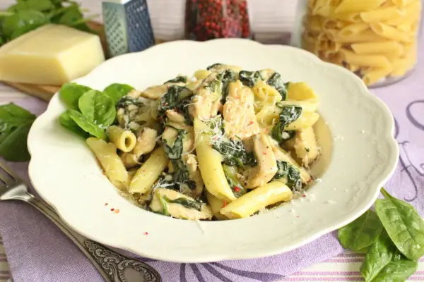 Penne z kurczakiem i szpinakiem w kremowym sosie, posypane parmezanem. Pyszne danie, które zachwyci każdego.